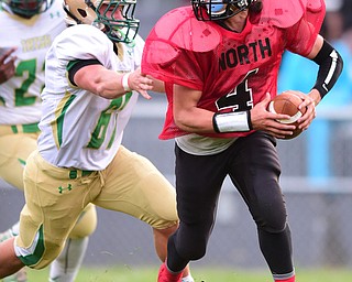 YOUNGSTOWN, OHIO - AUGUST 28, 2015: Quarterback James Boatwright III #4 of East rolls out to avoid pressure from defensive linemen Dante Cerimele #67 of Ursuline during the 1st half of a game Friday night at Rayen Stadium. DAVID DERMER | THE VINDICATOR
