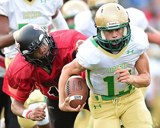 YOUNGSTOWN, OHIO - AUGUST 28, 2015: Quarterback Jared Fabry #13 of Ursuline runs upfield after avoiding the arm tackle from Mike Stevens #15 of East during the 1st half of a game Friday night at Rayen Stadium. DAVID DERMER | THE VINDICATOR