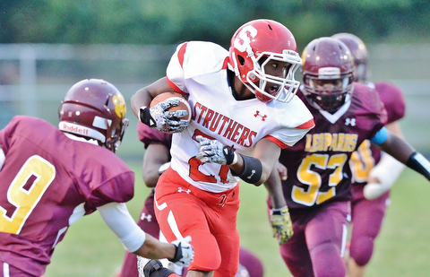 Jeff Lange | The Vindicator  AUGUST 28, 2015 - Struthers' Regal Reese (center) rushes for yards in between the defense of Liberty's Capone Haywood (left) and John Spivey in the first half of their game, Friday night in Liberty.