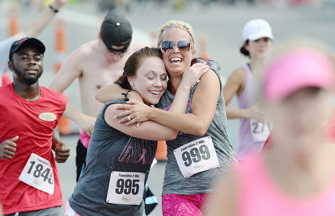Jeff Lange | The Vindicator AUGUST 30, 2015 - Stefanie Adams (left) and Carrie Ryan both of Boardman joyfully embrace one another as they cross the finish line of the two mile run portion of Sunday morning's Panerathon race, which donates all proceeds to the Joanie Abdu Comprehensive Breast Care Center. Ryan, a three year breast cancer survivor was one of nearly 10,000 participants in Sunday's race.