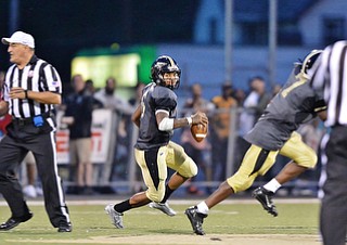 Jeff Lange | The Vindicator  SEPTEMBER 11, 2015 - Warren G. Harding quarterback Lynn Bowden (center) rolls out to the left while looking for a receiver during second quarter action against Massillon, Friday night in Warren.