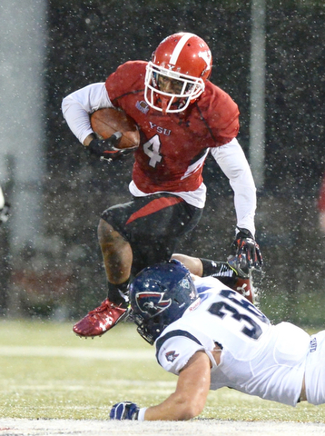 Jeff Lange | The Vindicator  SEPTEMBER 12, 2015 - YSU's Andre Stubbs (4) jumps over the tackle of Robert Morris' Cole Blake (36) in the first half of their game in Youngstown, Saturday evening.