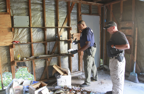 William d Lewis the Vindicator Communty Police offices Melvin Johnson, left, and Pat Kelly search a vacant garge on Youngstown's Southside where police found syringes and drug equipment Tuesday 9-22-15.