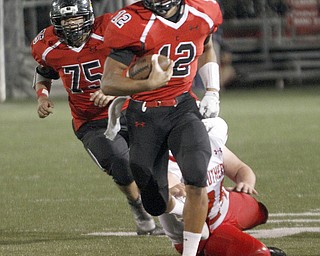       .         ROBERT  K. YOSAY | THE VINDICATOR..Canfields QB #12   Kato Kim breaks for a big gain as Strutehrs #24 Anthony Malone tries to grab with one hand #75 Canfield  Carmin Zena..struthers at canfied. -30-
