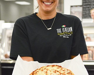 Katie Rickman | The Vindicator .Allie Rosati, Assistant Manager and daughter in law of the "Italian Marketplace" owners Pam and Donny DeVicchio, holds a pizza that is one of the top sellers at the store that also features a deli, italian foods, hot foods, and more.