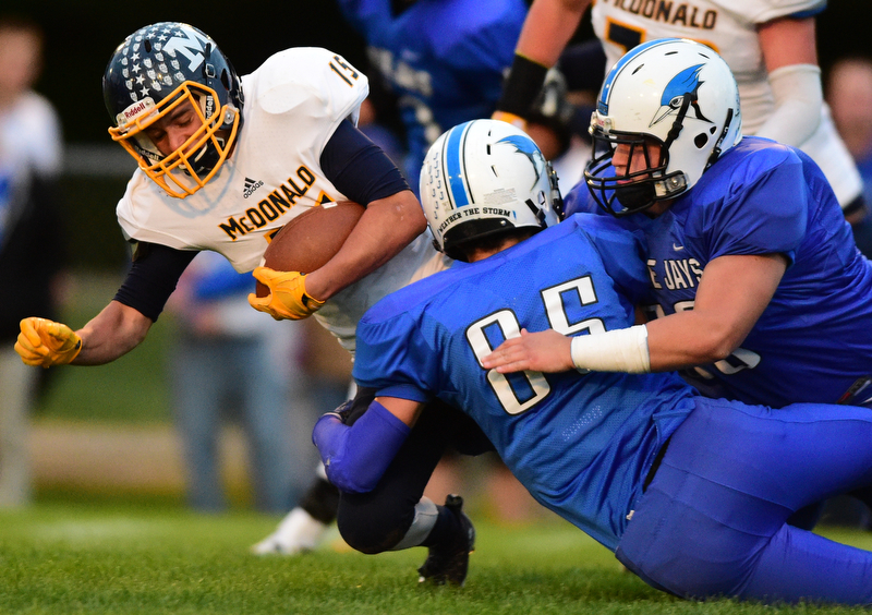 NORTH JACkSON, OHIO - OCTOBER 2, 2015: Joe Perry #15 of McDonald is tackled by Connon Kleinknecht #85 and Mason Mercer #58 of Jackson Milton during the 1st half of their game at Jackson Milton Stadium Friday night. DAVID DERMER | THE VINDICATOR