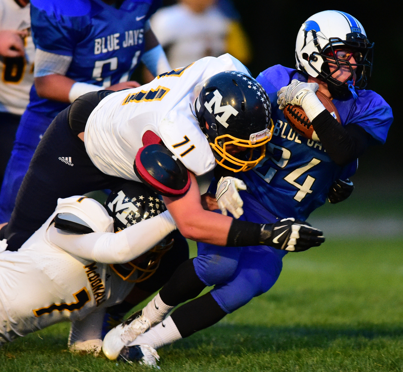 NORTH JACkSON, OHIO - OCTOBER 2, 2015: Joseph Burnside #24 of Jackson Milton is tackled by Drew Butler #71 and Ben Carkido #7 of McDonald during the 1st half of their game at Jackson Milton Stadium Friday night. DAVID DERMER | THE VINDICATOR