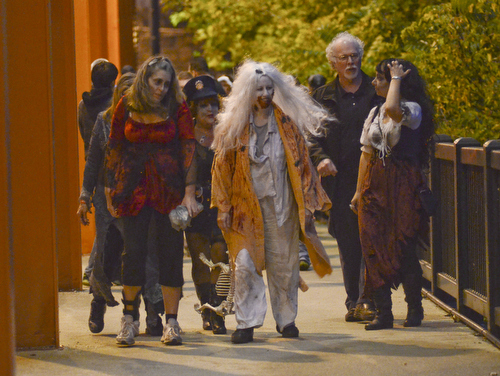 Katie Rickman | The Vindicator.Zombies stumble as they cross the Spring Commons Bridge during the fifth annual Zombie Crawl at the B&O in Youngstown on Saturday evening.