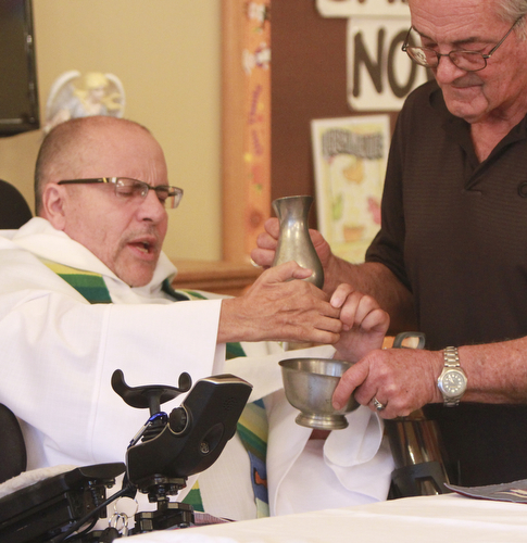 William D. Lewis The Vindicator Rev. Steve Popovich celebrates mass at Liberty Healthcare and Rehab. Popovich was paralized in a car crash. His brother Charlie helps wash popovich's hands.