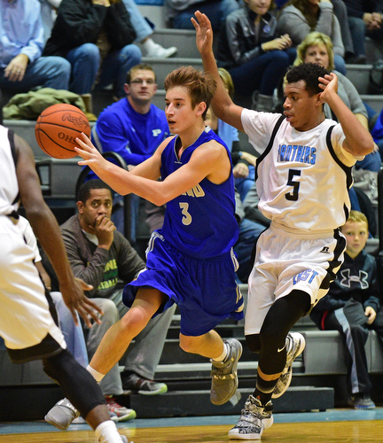 YOUNGSTOWN, OHIO - DECEMBER 4, 2015: Mike Gajdos #3 of Poland passes the ball to a teammate while being pressured from behind by Ceandre Backus #5 of East during the 2nd half of their game Friday night at East High School. DAVID DERMER | THE VINDICATOR
