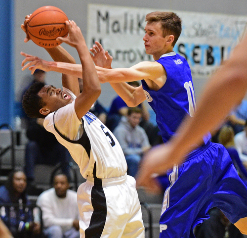 YOUNGSTOWN, OHIO - DECEMBER 4, 2015: Ceandre Backus #5 of East grabs the basketball while having the arm of Matt Baker #11 of Poland in his face during the 2nd half of their game Friday night at East High School. DAVID DERMER | THE VINDICATOR