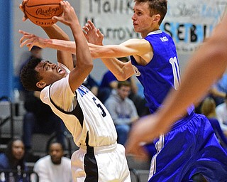 YOUNGSTOWN, OHIO - DECEMBER 4, 2015: Ceandre Backus #5 of East grabs the basketball while having the arm of Matt Baker #11 of Poland in his face during the 2nd half of their game Friday night at East High School. DAVID DERMER | THE VINDICATOR