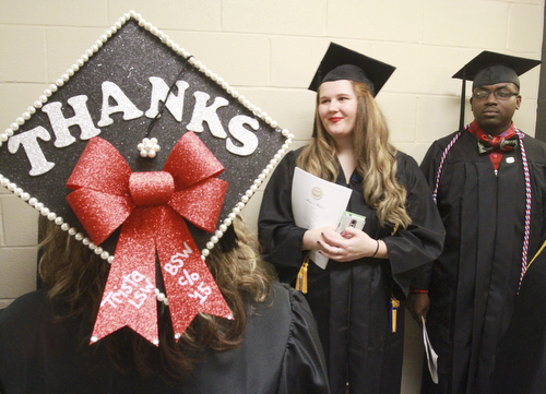 William D. Lewis the Vindicator Trista Goss of Youngstown uses her motar board to say she has a lot to be thankful for as she graduated from YSU with a bachelor in Social Work Sunday. Looking on are fellow grads Amy Van Fossan of Boardman and Kevin R. Wallace of Youngstown.