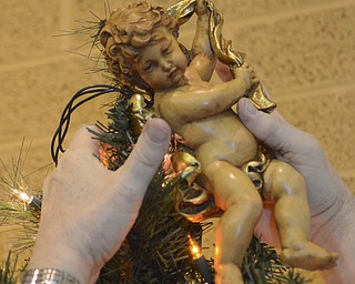 Katie Ricman | The Vindicator.Rev. Dave Merzwiller reaches up and places a cherub on a Christmas tree on the alter at St. Catherine Church in Lake Milton on December 22, 2015.