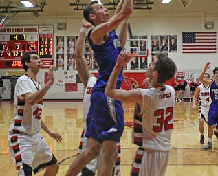 Poland's Matt Baker (11) jumps over the defense set up by Canfield's Julian Vitto (32) and Sam Digiacomo (42) during Friday nights matchup at Canfield High School.  Dustin Livesay  |  The Vindicator  1/29/16  Canfield High School.