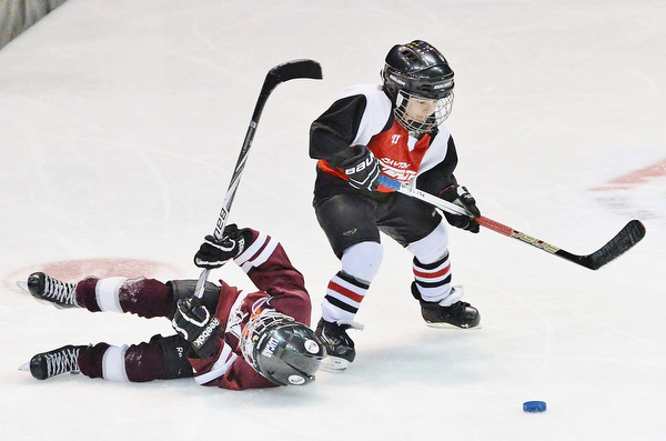 Jeff Lange | The Vindicator  SUN, MAR 6, 2016 - Seven-year-old Jace Lisk of Dayton Stealth (right) takes a shot as Johnstown Warriors' Lucas Lecorchick topples to the ice in the second period of their game during the Phantoms ADM Fantastic Finale 4-8 year old Tournament held at the Covelli Centre and Ice Zone in Boardman on Saturday and Sunday.