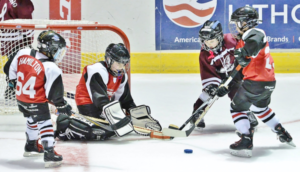 Jeff Lange | The Vindicator  SUN, MAR 6, 2016 - Dayton Stealth goalie Joey Kaczmarek (center) blocks the shot of Johnstown Warriors' Keaton Farabaugh (right) during Kaczmarek's first shutout game of the season as Dayton's Tyler Hamilton (64) and Colbin Wolf (far right) look on during the Phantoms ADM Fantastic Finale 4-8 year old Tournament held at the Covelli Centre and Ice Zone in Boardman on Sunday. The Stealth claimed third place by defeating the Warriors 6-0.