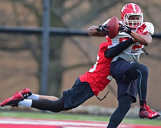 YOUNGSTOWN, OHIO - MARCH 18, 2016: Will Mahone (white)secures the football while being tackled by Jalyn Powell (red) during a 7 on 7 passing drill during the teams practice Friday afternoon at Stambaugh Stadium. DAVID DERMER | THE VINDICATOR