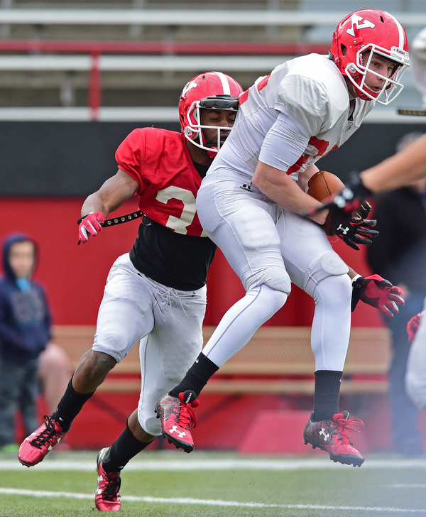 YOUNGSTOWN, OHIO - MARCH 23, 2016: Zack Torbert (white) catches a pass in the air before David Rivers (red) can wrap him up and tackle him during the teams practice Wednesday afternoon at Stambaugh Stadium. DAVID DERMER | THE VINDICATOR