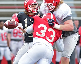 YOUNGSTOWN, OHIO - MARCH 23, 2016: Ricky Davis #12 of YSU throws a pass from the pocket behind the block of Jeff Rotheram (white) on Johnson Louigene (red) during the teams practice Wednesday afternoon at Stambaugh Stadium. DAVID DERMER | THE VINDICATOR