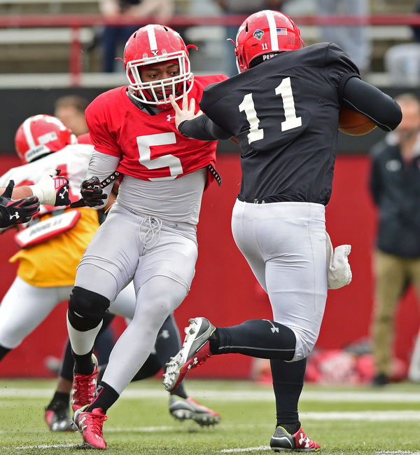 YOUNGSTOWN, OHIO - MARCH 23, 2016: Lee Wright (red) is stiff armed by Trent Hosick (black) before sacking him in the backfield for a loss during the teams practice Wednesday afternoon at Stambaugh Stadium. DAVID DERMER | THE VINDICATOR..