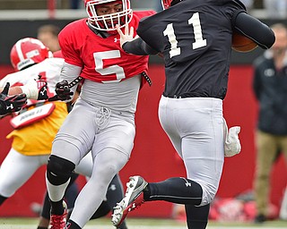 YOUNGSTOWN, OHIO - MARCH 23, 2016: Lee Wright (red) is stiff armed by Trent Hosick (black) before sacking him in the backfield for a loss during the teams practice Wednesday afternoon at Stambaugh Stadium. DAVID DERMER | THE VINDICATOR..
