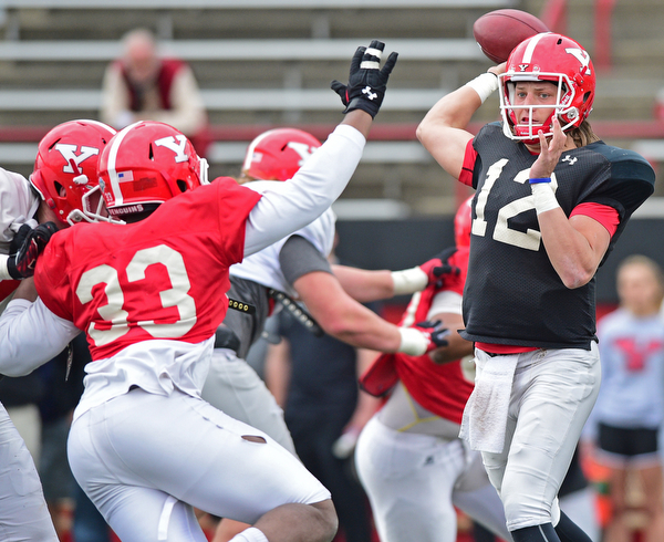 YOUNGSTOWN, OHIO - MARCH 23, 2016: Ricky Davis #12 of YSU throws a pass while being pressured by Johnson Louigene (red) during the teams practice Wednesday afternoon at Stambaugh Stadium. DAVID DERMER | THE VINDICATOR