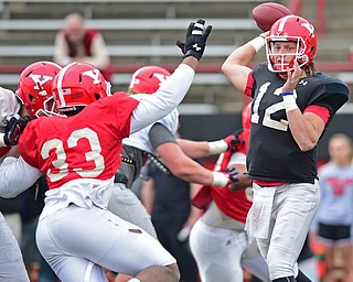 YOUNGSTOWN, OHIO - MARCH 23, 2016: Ricky Davis #12 of YSU throws a pass while being pressured by Johnson Louigene (red) during the teams practice Wednesday afternoon at Stambaugh Stadium. DAVID DERMER | THE VINDICATOR