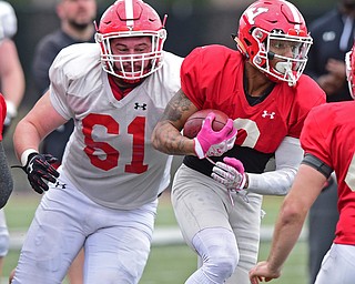YOUNGSTOWN, OHIO - MARCH 23, 2016: LeRoy Alexander (red) spins away from Justin Spencer (white) while running with the football after a interception during the teams practice Wednesday afternoon at Stambaugh Stadium. DAVID DERMER | THE VINDICATOR