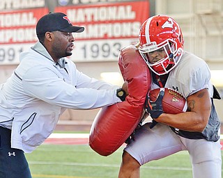 Jeff Lange | The Vindicator  SAT, APRIL 2, 2016 - YSU RB Coach Nic McKissic-Luke (left) slams tailback Roosevelt Griffin with a pad during running back drills at the Watson and Tressel Training Site on Saturday.