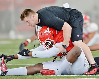 Jeff Lange | The Vindicator  SAT, APRIL 2, 2016 - YSU Assistant Strength and Conditioning Coordinator Mark Brandenstein (top) helps linebacker Johnson Louigene stretch prior to the start of Saturday's practice at the Watson and Tressel Training Site in Youngstown.