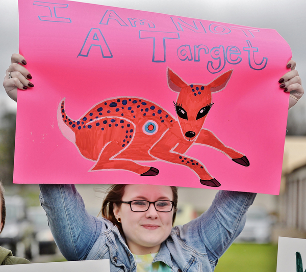 Jeff Lange | The Vindicator  MON, APRIL 4, 2016 - Ashley Molnar of Niles raises a sign above her head during a protest against the opening of Candywood Whitetail Ranch on Monday evening in Vienna. "I feel like they should be turning the land into a nature preserve. Breeding animals to kill them is not right," Molnar said.