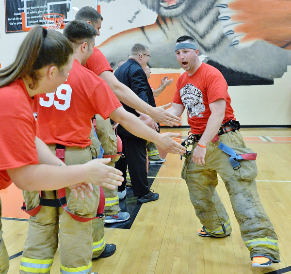 Jeff Lange | The Vindicator  FRI, APRIL 22, 2016 - Team Fire captain Kevin Bloom (right) high fives teammates during pregame announcements of the Guns vs. Hoses game at Howland High School Friday night.