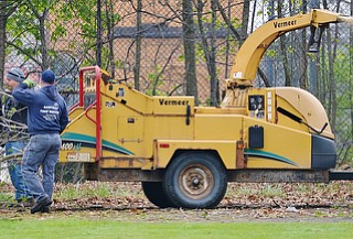 Jeff Lange | The Vindicator  SAT, APRIL 30, 2016 - Volunteers work together to put unwanted tree limbs into a wood chipper Saturday morning during the Boys and Girls Club backyard cleanup in Youngstown.