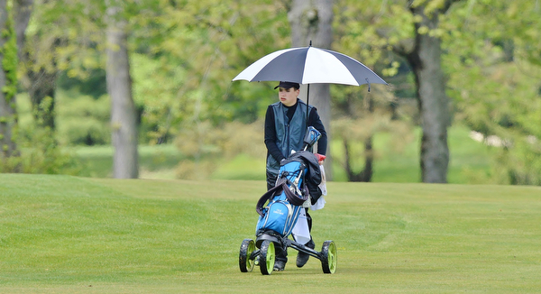 Jeff Lange | The Vindicator  SUN, MAY 15, 2016 - Boardman's Cole Christman walks down the fairway under the shade of an umbrella during Sunday's Greatest Golfer of the Valley junior event at Avalon Lakes at Squaw Creek.