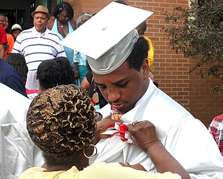 Nikos Frazier | The Youngstown Vindicator..Dayshawn Mims(right) talks with his grandmother, Theressa Mims, as she adjusts a flower on his graduation gown after Dayshawn received his diploma from Chaney Campus High School.