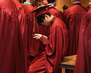 Nikos Frazier | The Vindicator..A Cardinal Mooney High School student looks at his phone before lining up in Stambaugh Auditorium to receive his diploma.
