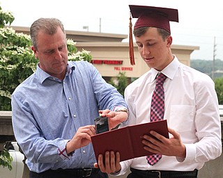 Nikos Frazier | The Vindicator..Mark Braydich(left) takes a picture of his son, Nick Braydich's diploma after Nick graduated from Cardinal Mooney High School.
