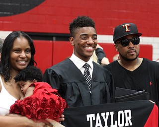 Nikos Frazier | The Vindicator..CorrionTaylor(center) smiles as he takes pictures with his parents, Latoya Coston(left) and Harry Taylor(right), after graduating from Canfield High School,