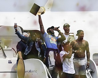 Cleveland Cavaliers' Lebron James, center, holds up the NBA Championship trophy alongside teammates Kyrie Irving, left, Kevin Love, rear right, J.R. Smith, right, and Tristan Thompson, front,   at the airport in Cleveland, Monday, June 20, 2016. (AP Photo/John Minchillo)