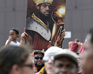 A man holds up a photo of Cleveland Cavaliers' LeBron James as he waits the arrival of the team in Cleveland, Monday, June 20, 2016. Lebron James came home with the trophy he promised, and the championship Cleveland has coveted for 52 years. The NBA superstar, born and raised in nearby Akron, stepped off a plane Monday and hoisted the shiny Larry O'Brien Trophy as more than 10,000 fans celebrated the city's first title since 1964. (AP Photo/Tony Dejak)