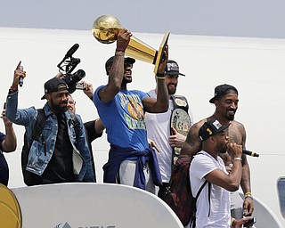 Cleveland Cavaliers' LeBron James holds up the NBA Championship trophy alongside teammates after arriving in Cleveland, Monday, June 20, 2016. (AP Photo/Tony Dejak)
