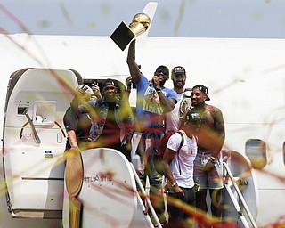 NBA champion Cleveland Cavaliers Lebron James, center, holds up the NBA championship trophy alongside teammates Kyrie Irving, left, Kevin Love, rear right, J.R. Smith, right, and Tristan Thompson, front, as they arrive at the airport Monday, June 20, 2016, in Cleveland.  (AP Photo/John Minchillo)