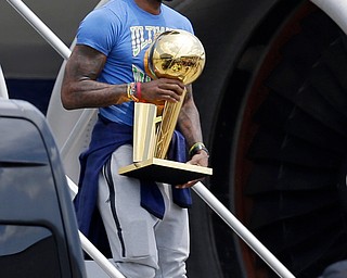 Cleveland Cavaliers' LeBron James carries The Larry O'Brien NBA Championship Trophy after arriving in Cleveland, Monday, June 20, 2016. (AP Photo/Tony Dejak)
