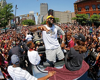 Cleveland Cavaliers' LeBron James, center, stands in the back of a Rolls Royce as it makes it way through the crowd lining the parade route in downtown Cleveland, Wedensday, June 22, 2016, celebrating the Cleveland Cavaliers' NBA Championship. (AP Photo/Gene J. Puskar)