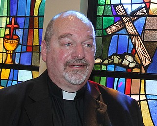 William D. Lewis/The Vindicator Rev. Frank Zanni, pastor St. Thomas The Apostle with stained glass windows of new church.