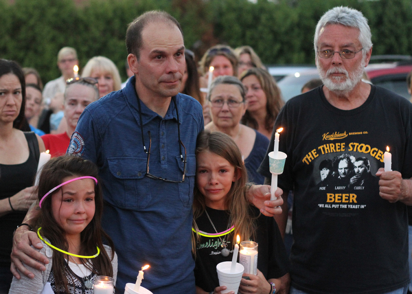 Nikos Frazier | The Vindicator..Jimmy Taafe(center) puts his arms around his daughters, Gianna(left), 9 and Mickayla(right), 10 at a candlelight vigil for his late wife, Kristy Wolfe Taafe, who died unexpectedly Sunday. Ray Wolfe, Kristy's father, holds two candles on the right.