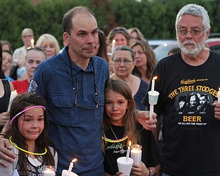 Nikos Frazier | The Vindicator..Jimmy Taafe(center) puts his arms around his daughters, Gianna(left), 9 and Mickayla(right), 10 at a candlelight vigil for his late wife, Kristy Wolfe Taafe, who died unexpectedly Sunday. Ray Wolfe, Kristy's father, holds two candles on the right.