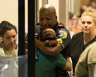 A Dallas Area Rapid Transit police officer receives comfort at the Baylor University Hospital emergency room entrance Thursday, July 7, 2016, in Dallas. Police say one rapid-transit officer has been killed and three injured when gunfire erupted during a protest in downtown Dallas over recent fatal shootings by police in Louisiana and Minnesota. (Ting Shen | The Dallas Morning News via AP)