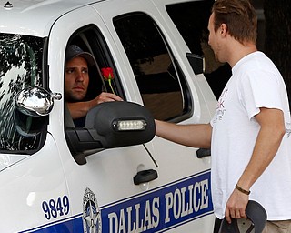 John Fife  hands a police officer guarding Jack Evans Police Headquarters a rose in Dallas on Friday July 8, 2016. Snipers opened fire on police officers in the heart of Dallas during protests over two recent fatal police shootings of black men. (Nathan Hunsinger | The Dallas Morning News via AP)